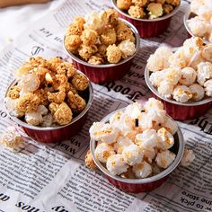 four red cups filled with popcorn sitting on top of a newspaper