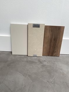 three different types of tile are lined up against the wall, one is brown and one is white