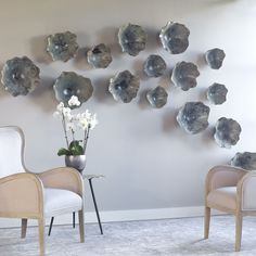 two chairs are facing each other in front of a wall with silver flowers on it