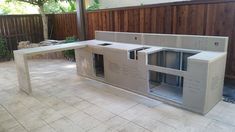 an outdoor kitchen made out of cinder blocks with windows and sliding doors on the side