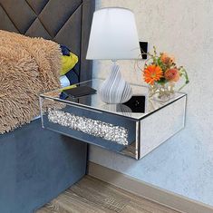 a nightstand with a glass drawer on it and a teddy bear sitting in the corner