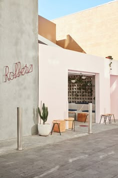 a white building with red lettering on the side and some chairs in front of it