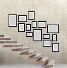 there are many frames on the wall above the stairs