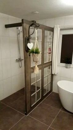 a bathroom with a bathtub, sink and window in the corner that has plants hanging from it