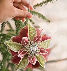 someone is decorating a christmas tree with red and green decorations on the top ornament