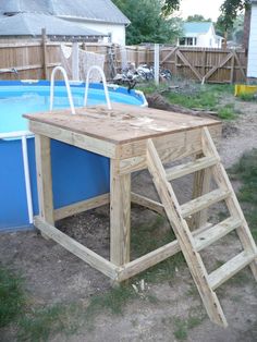 a wooden table sitting in the middle of a yard next to an above ground pool