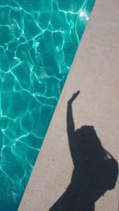 a shadow of a person standing next to a swimming pool