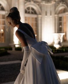 a woman in a white dress is standing outside at night with her back to the camera