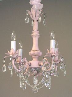 a white chandelier hanging from the ceiling with crystal drops on it's arms