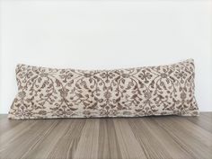 a pillow sitting on top of a wooden floor next to a white wall and wood floor