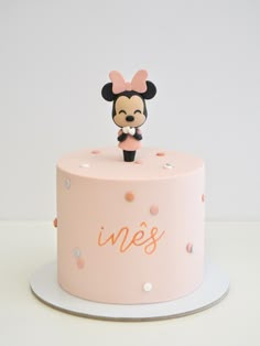 a pink cake decorated with a minnie mouse figurine