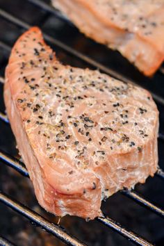 two pieces of meat cooking on top of an open grill with black pepper sprinkles