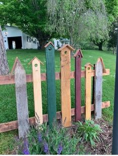 a fence made out of wooden boards in the grass with flowers growing next to it