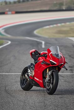 a red motorcycle parked on the side of a race track