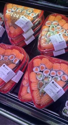 several trays of sushi are on display in a case