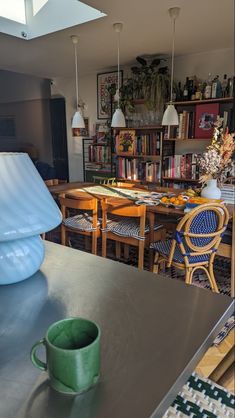 a table with a green cup on top of it next to a book shelf filled with books