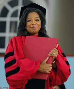 a woman in graduation gown holding a red folder