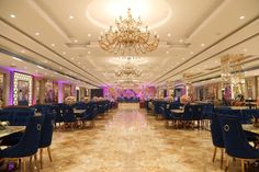 a fancy dining room with chandeliers and blue velvet chairs on the floor,