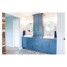 a large bathroom with blue cabinets and two mirrors on the side of the vanity area