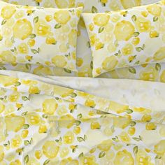 a yellow and white bed with lemons printed on the sheets, along with matching pillow cases