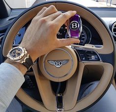 a person is driving a car with their hand on the steering wheel while holding a cell phone