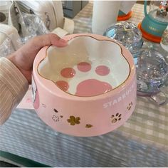 a person is holding a pink bowl on a table