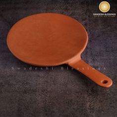 an orange frying pan sitting on top of a black countertop next to a gray wall