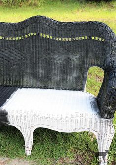 a black and white wicker bench sitting in the grass