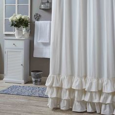 a white shower curtain with ruffles on the bottom is in front of a mirror