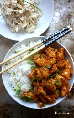 two plates with rice, chicken and chopsticks