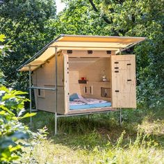 an outhouse in the woods with a bed inside