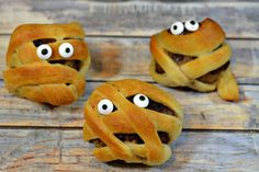 three pastries with googly eyes on them sitting on top of a wooden table