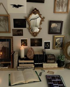 an open book sitting on top of a table next to a mirror and some pictures