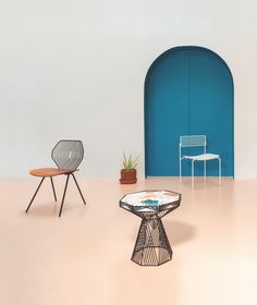 two chairs and a table in front of a blue wall with an arch at the end