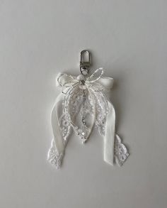 the white ribbon is attached to the keychain with a bow and bead