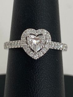 a heart shaped diamond ring sitting on top of a black leather band with diamonds around it