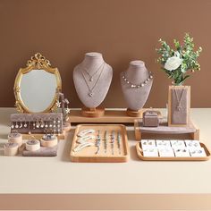 an assortment of jewelry on display in front of a mirror and vase with white flowers