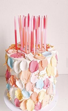 a multi - layered cake with pink candles on top is decorated in pastel colors