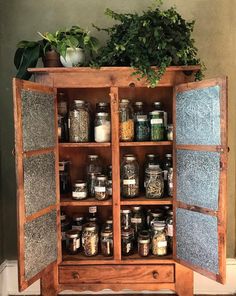 an old wooden cabinet filled with lots of jars and spices next to a potted plant