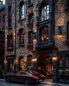 a red sports car parked in front of a tall brick building with windows and balconies