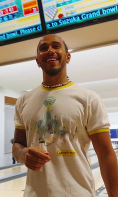 a man standing in front of a bowling alley holding a glass of wine and smiling at the camera