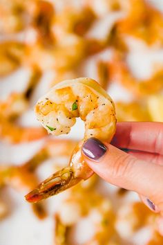 a hand holding up a piece of food with shrimp on it's tip and the other side