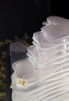 a stack of plastic trays filled with food on top of a table next to plants