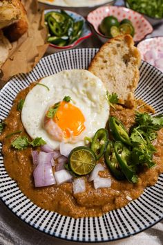 a plate with some food on it and bread in the background, along with other dishes