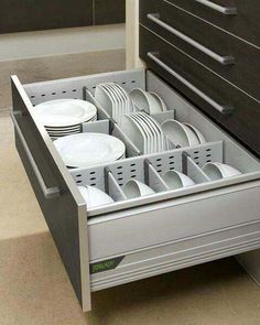 an open drawer with plates and cups in it