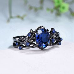 a ring with blue stones on it sitting on top of a white surface next to flowers