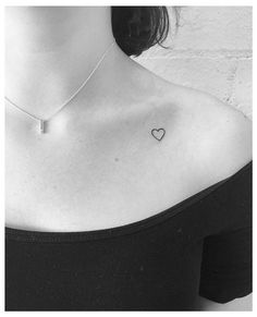 a black and white photo of a woman's chest with a heart tattoo on it