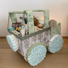 a stuffed animal in a toy car on a wooden floor next to a white wall