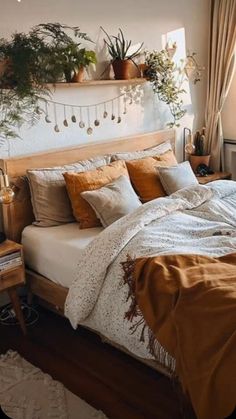 a bed sitting in a bedroom next to a window with potted plants on top of it