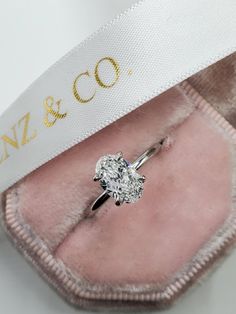 an engagement ring with a diamond on it in a pink velvet box that says, love & co